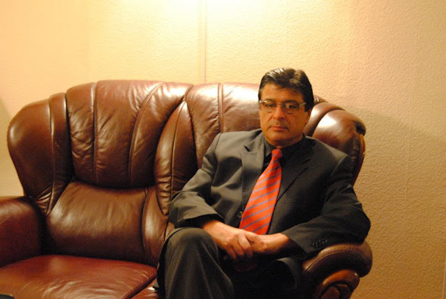 Isa Sadykov is seated at a desk.