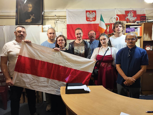 Participants at the Larisa Heniush memorial in Warsaw hold a Belarusian flag.
